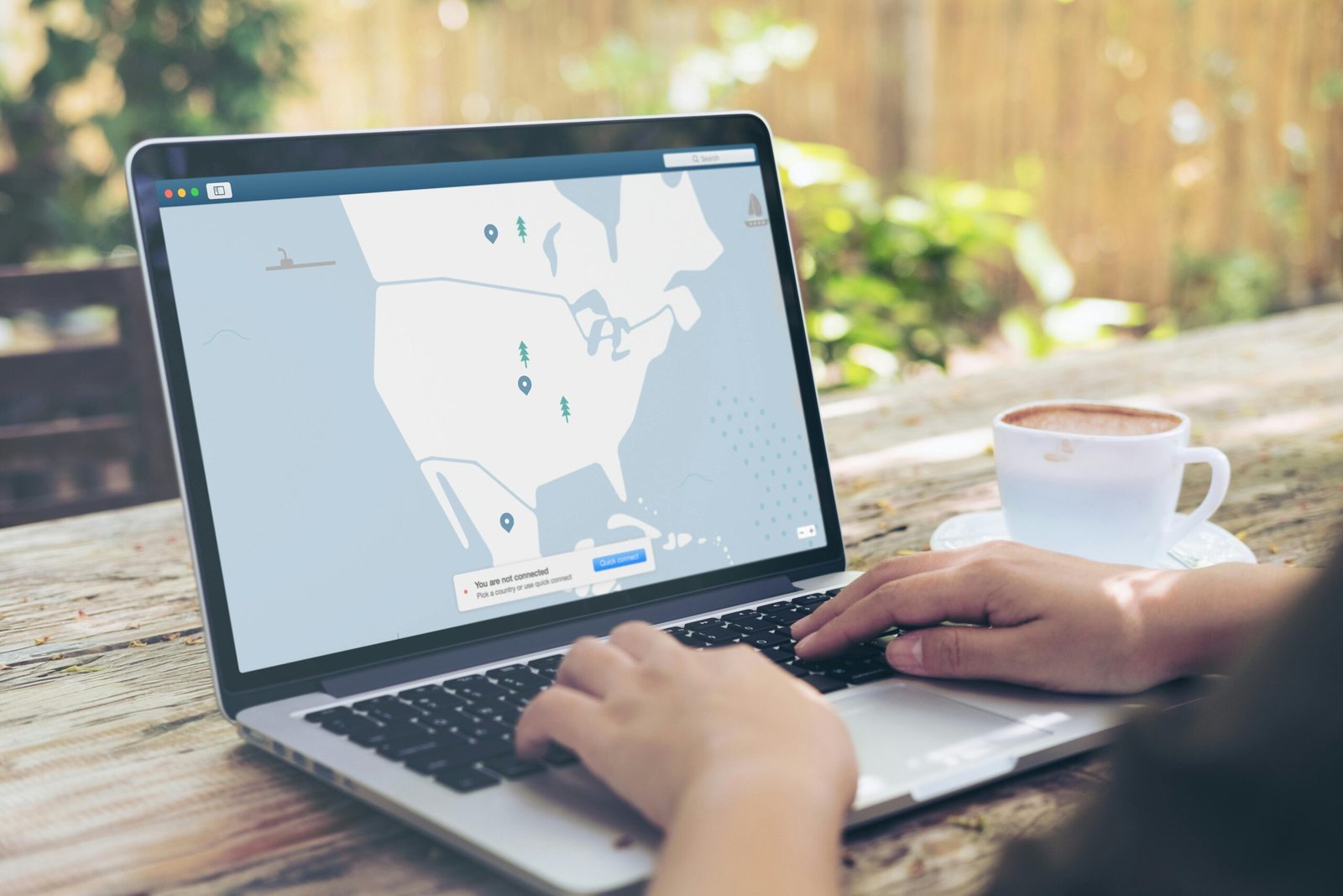pexels-photo-1923286-1923286 Hands typing on a laptop outdoors with a VPN interface displayed, next to a cup of coffee.
